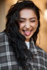Naklejka premium Happy woman with dark hair playfully sticks out her tongue, smiling.