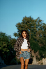 Smiling woman in casual attire posing outdoors with a clear blue sky backdrop.