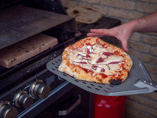 Taking a Freshly Baked Homemade Pizza out of the Oven