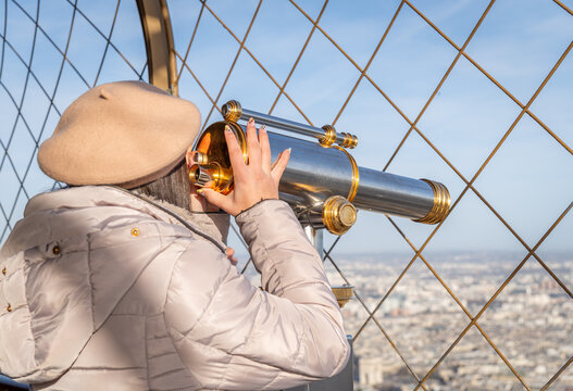 Woman viewing Paris through telescope at Eiffel Tower