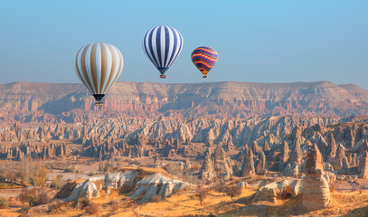 Hot air balloon flying over fairy chimneys and rock landscape at Cappadocia, Turkey