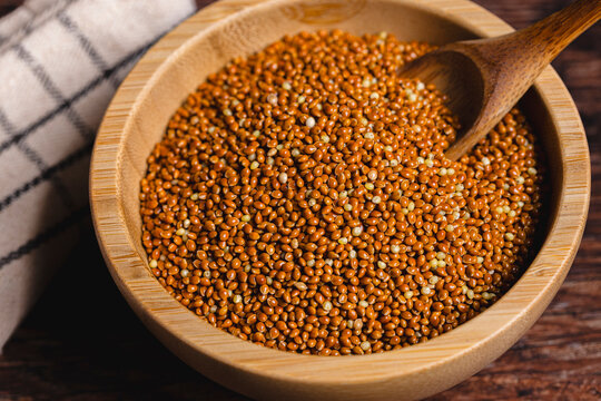From above of brown millet in wooden bowl with spoon