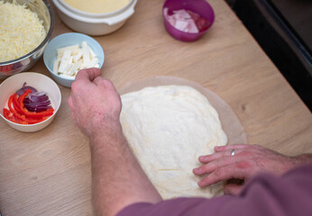  Man's Hands Stretching Homemade Pizza Dough on a Wooden Counter