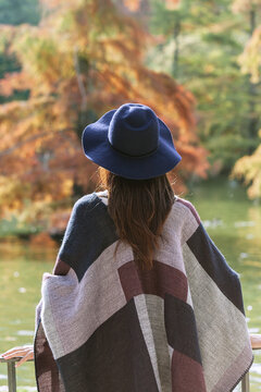 Woman in hat enjoys serene autumn scenery by lake