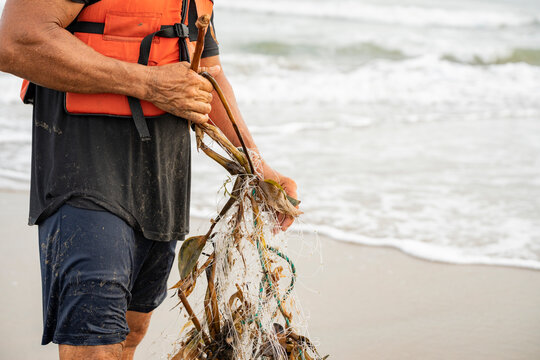 Unrecognizable fisherman struggling with ocean pollution