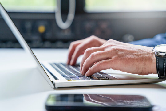 Hands typing on laptop keyboard at office desk during business work