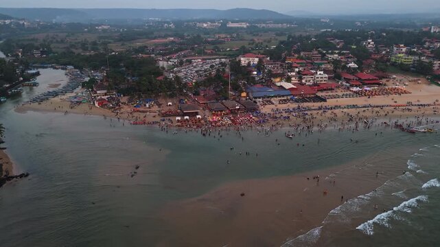 Panoramic drone shot of a party at the Baga beach, hazy sunset in Goa, India