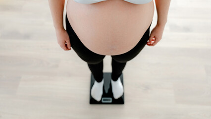 Pregnant woman checking weight on a scale