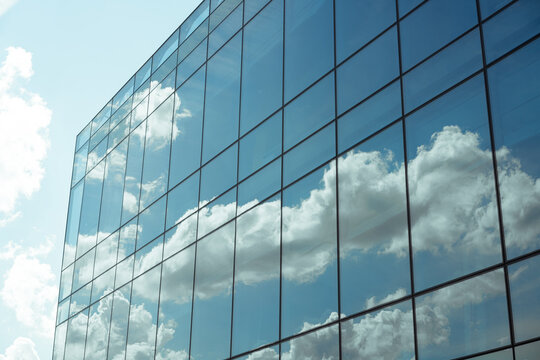 Modern glass building reflecting sky and clouds