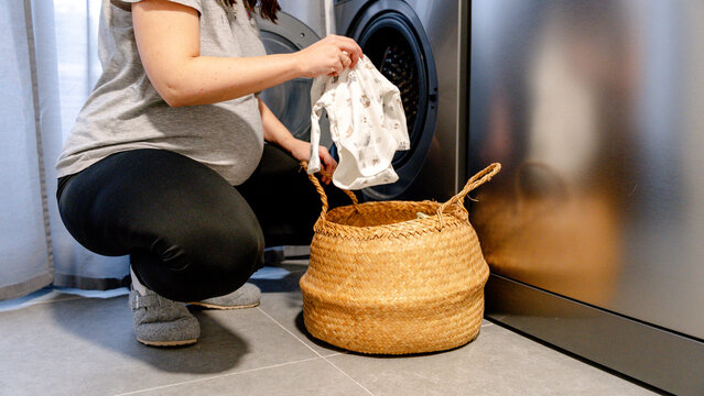 Preparing baby clothes for washing by future mother