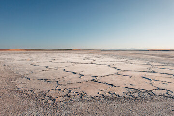 Dry cracked surface of salt flat under clear blue sky