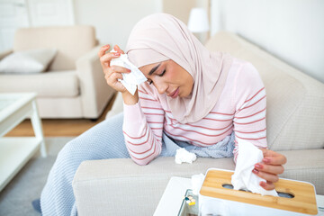 Sick day at home. Young Arabic woman has runny and common cold. Cough. Closeup Of Beautiful Young Woman with hijab Caught Cold Or Flu Illness.