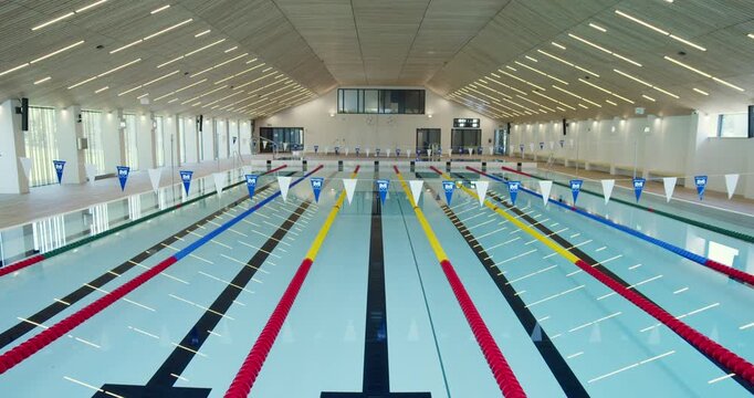 A wide view of a state-of-the-art public swimming pool with a movable floor. Colorful lane lines stretch across the calm water. This modern aquatic facility is ready for any activity or competition.