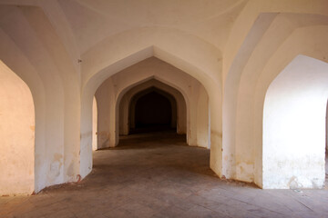 An interior view of a historic Indian fortress, featuring a repeating pattern of white-washed arched doorways, creating a sense of depth and symmetry. Ideal for travel guides and architectural history