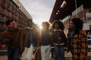 Obraz premium Happy multiracial friends walking together in the city at sunset