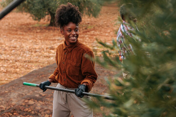 Smiling farmer holding rake harvesting olives in olive grove