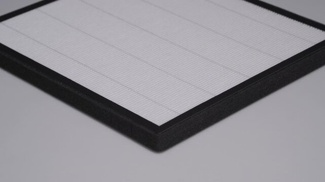 A brand new, clean HEPA filter for an air purifier, shot in a studio on a neutral grey background. The pleated filter medium is designed to trap allergens, dust, and pollutants from the air.