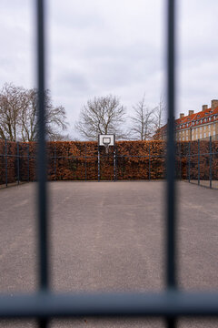 Blurred metal fence in front of outdoor sports court, emphasizing perspective, security, boundaries, and urban community lifestyle within minimalist architectural compositions and contexts.