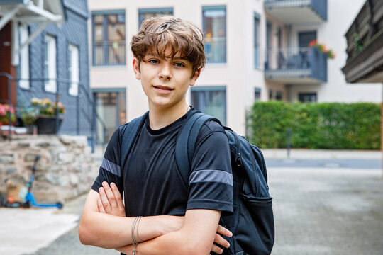Teenage boy with backpack walking outdoors on the way to school. Student going back to school, education and daily lifestyle concept.