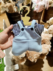 Miniature blue overalls with striped shirt for stuffed toy displayed with plush toys.
