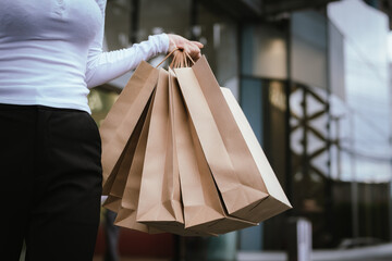 Close-up of a hand holding a paper shopping bag, which is a symbol of buying, selling, lifestyle, style, glamour and shopping culture in modern cities.