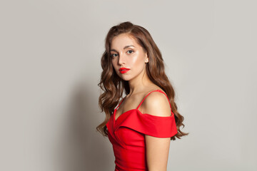 Fototapeta premium Good-looking fashion model woman with shiny skin, wavy hairstyle and red lips makeup on black background