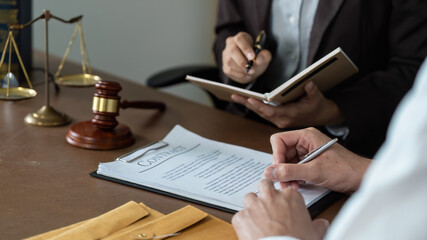 Contract Review. Lawyer taking notes while discussing legal documents with a client.