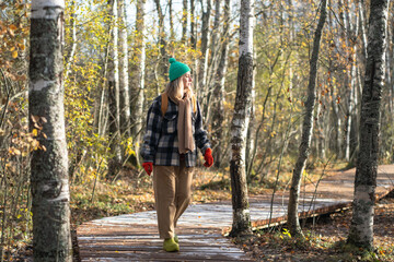 Interested woman tourist enjoy stroll on forest path in cold fall day. Female wearing warm clothes walks in park, breathing cool fall air observing changes in nature. Solo travel, time alone in woods