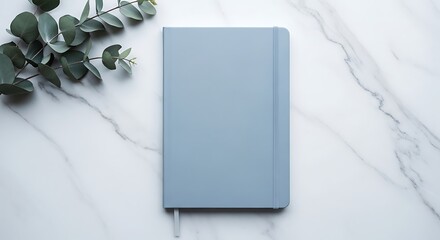 Modern blue notebook on marble surface with green leaves top view