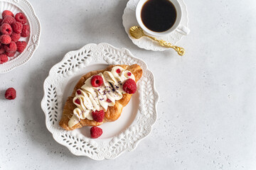 Trendy viral flat croissant on white plate, coffee. Delicious buttery thin croissant with fresh raspberry, cream. french breakfast. Crusty flat croissant recipe, bakery, cafe menu, copy space top view