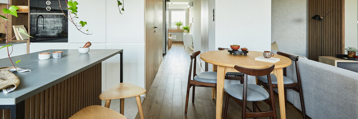 Stylish kitchen interior design with dining space. Workspace with kitchen accessories on the back ground. Creative walls with woode pannels. Minimalistic style an plant love concept.