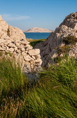 Croatia, Europe: a glimpse of Rucica, the pebbled beach nestled in a barren bay with little green plants and desert landscape to the southeast of the village of Metajna, on the famous Pag 