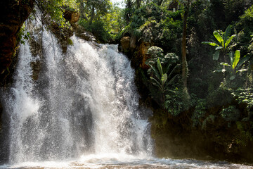 El Molino waterfall in Valle de Bravo, Mexico, cascading over dark rocks into a calm pool, lush vegetation around reflecting a peaceful hidden sanctuary, ideal for ecotourism and serene green travel