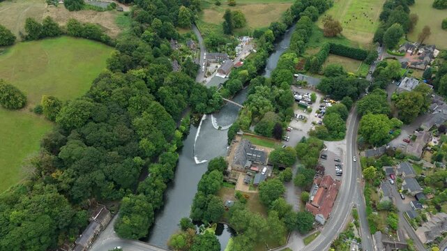 Top down aerial drone view of large bow shaped Weir on river Derwent, water control structure, Millbrook in Derbyshire Dales in England UK