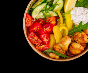Fresh salad bowl with grilled chicken and vibrant vegetables on black background