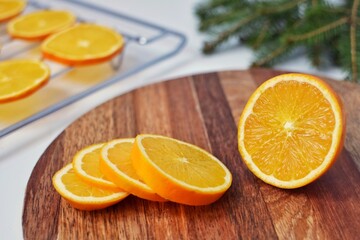 Slice the orange on a wooden board for further drying on a baking sheet in the oven, for Christmas decoration