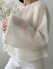 Softly illuminating serenity, a woman of Asian descent cradles delicate baby's breath; celebrate Hygge bliss and Knitwear Day