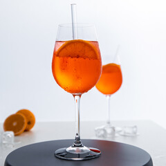 Glas mit leuchtend orangefarbenem Aperol Spritz Cocktail, verziert mit Eiswürfeln, einer frischen Orangenscheibe und einem stilvollen Trinkhalm