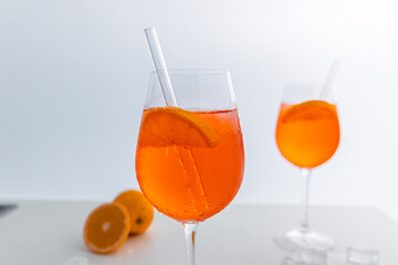 Glas mit leuchtend orangefarbenem Aperol Spritz Cocktail, verziert mit Eiswürfeln, einer frischen Orangenscheibe und einem stilvollen Trinkhalm