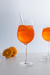 Glas mit leuchtend orangefarbenem Aperol Spritz Cocktail, verziert mit Eiswürfeln, einer frischen Orangenscheibe und einem stilvollen Trinkhalm