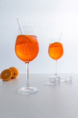 Glas mit leuchtend orangefarbenem Aperol Spritz Cocktail, verziert mit Eiswürfeln, einer frischen Orangenscheibe und einem stilvollen Trinkhalm