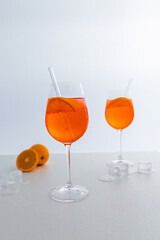 Glas mit leuchtend orangefarbenem Aperol Spritz Cocktail, verziert mit Eiswürfeln, einer frischen Orangenscheibe und einem stilvollen Trinkhalm