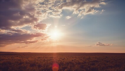 Dramatic sunset over a vast open field, with vibrant colors and scattered clouds creating a serene atmosphere