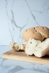 Sliced homemade bread resting on wooden cutting board on marble table