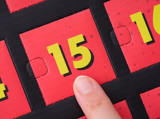 Woman finger pointing at the number 15 on an advent calendar.