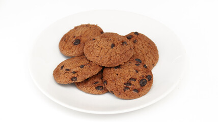 Isolated clipping path of die cut dark chocolate chip cookies on white plate. Closeup tasty bakery organic homemade American biscuit sweet dessert