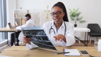 Young adult female doctor analyzing radiographic images in clinical setting, showcasing professionalism. Scene depicts medical expertise, technology usage, and patient care in healthcare workplace - Powered by Adobe