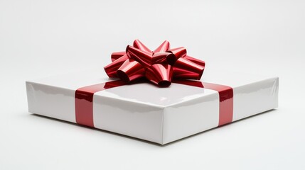 A pristine white gift box is centered on a white surface. A large, glossy red satin bow is elegantly tied on top of the box, creating a striking contrast. 