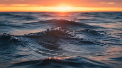 Obraz premium Gentle ocean waves ripple under a warm sunset glow, evoking peace and tranquility.