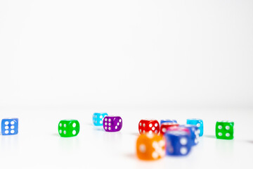 Colorful scattered dice on white background with focus on orange die in foreground